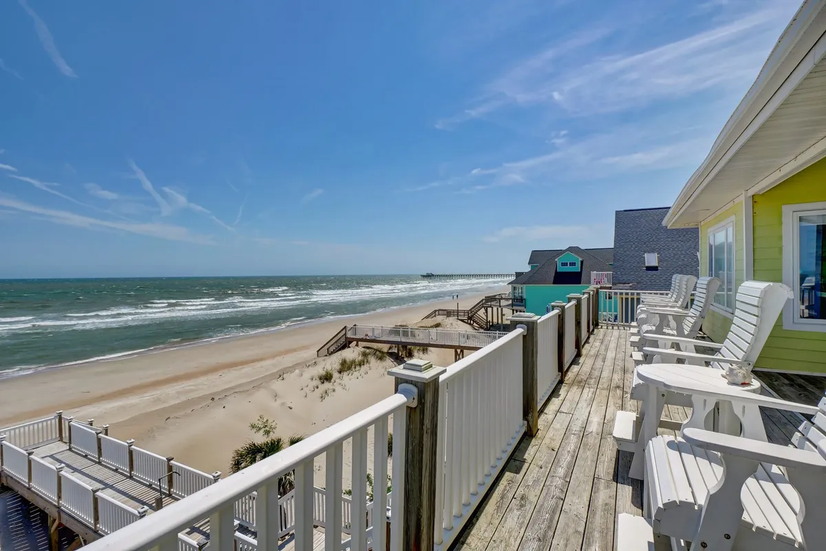 Deck chairs set up to face a vibrant beach scene, where ocean waves roll in and the pier can be glimpsed in the distance. The setup is ideal for sunbathing, gathering with friends, or watching the sunrise, showcasing both relaxation and togetherness.